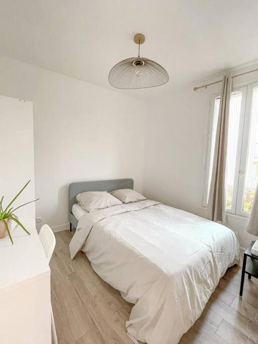 - une chambre blanche avec un lit et une lampe dans l'établissement Le Saint-Ouen proche Paris, à Saint-Ouen