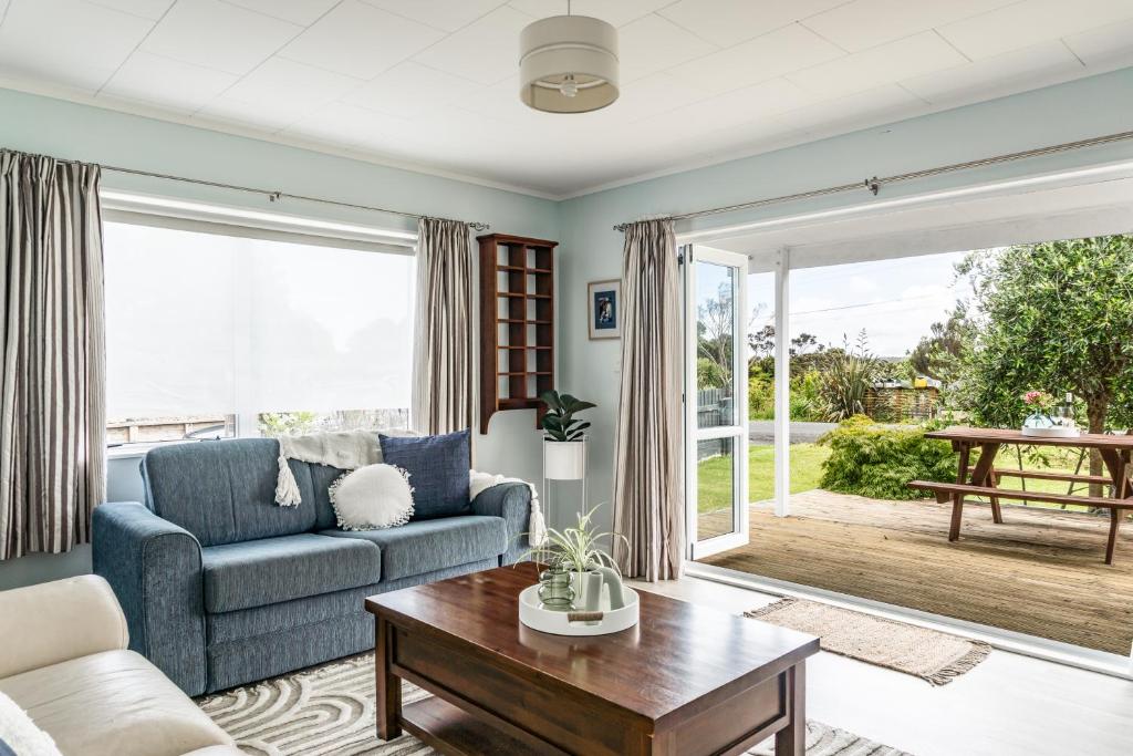 a living room with a couch and a table at Calypso Cottage in Raglan