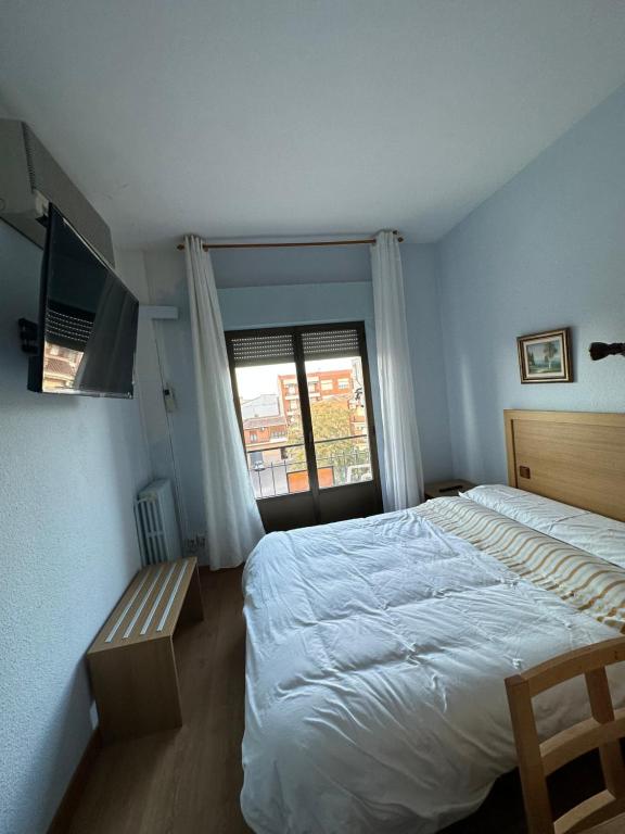 Un dormitorio con una cama grande y una ventana en Hostal agripino y Restaurante asiático, en Mora