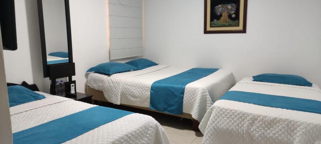 Habitación con 2 camas y sábanas azules y blancas. en Hotel Mykonos Manta en Manta
