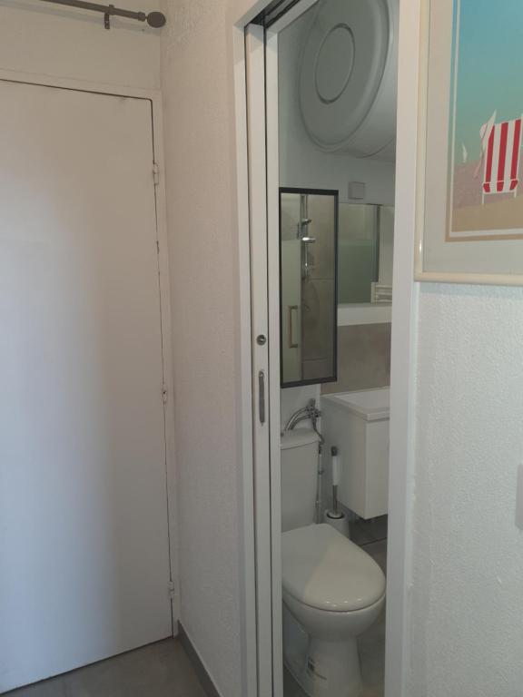 La salle de bains blanche est pourvue de toilettes et d'un miroir. dans l'établissement Quatro la corniche, à Sète