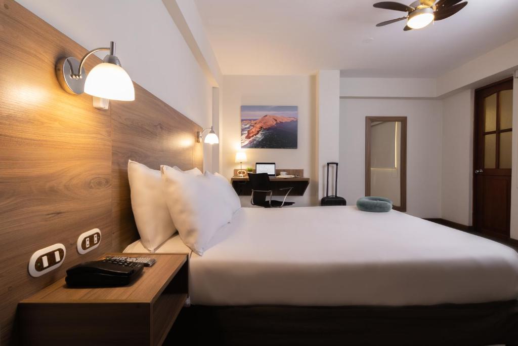 een hotelkamer met een groot bed en een bureau bij Hotel Alexander in Trujillo