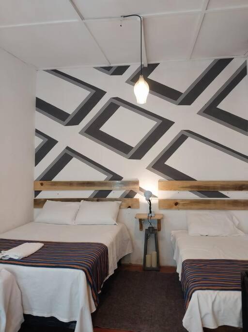 Duas camas num quarto com um tecto estampado em Casa Xejulya em San Pedro La Laguna