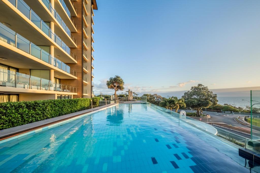 a swimming pool in a building with a view of the ocean at Oaks Redcliffe Mon Komo Suites in Redcliffe