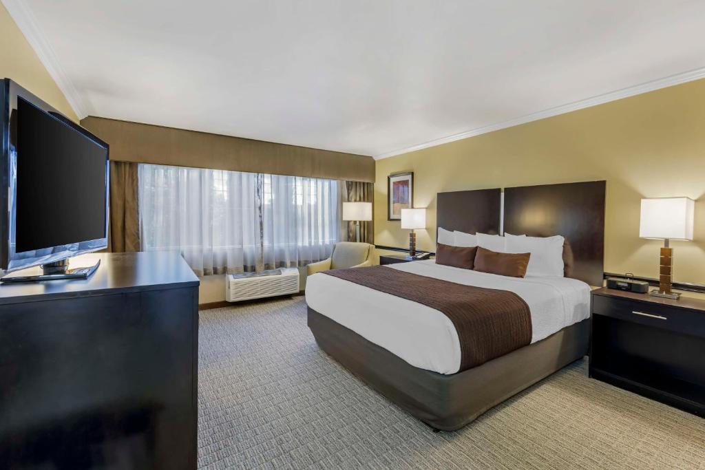 a hotel room with a bed and a flat screen tv at Best Western Canoga Park Motor Inn in Canoga Park