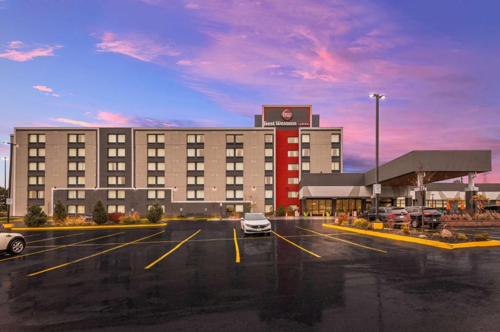 a hotel with cars parked in a parking lot at Best Western Plus Toronto North York Hotel & Suites in Toronto