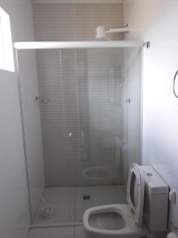 a white bathroom with a toilet and a shower at Casa da Praia in Florianópolis