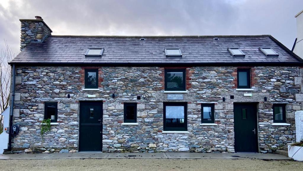 a stone house with black doors and windows at Bill's Barns, Apartment 1 in Kenmare