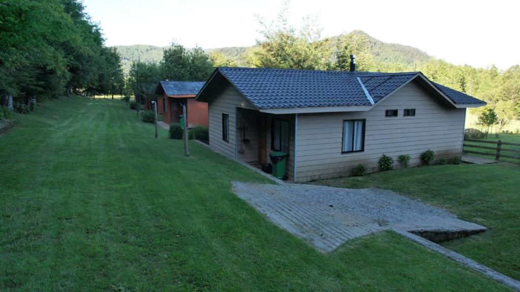 una pequeña casa en un campo con un patio de césped en Cabañas de la Barra, en Villarrica