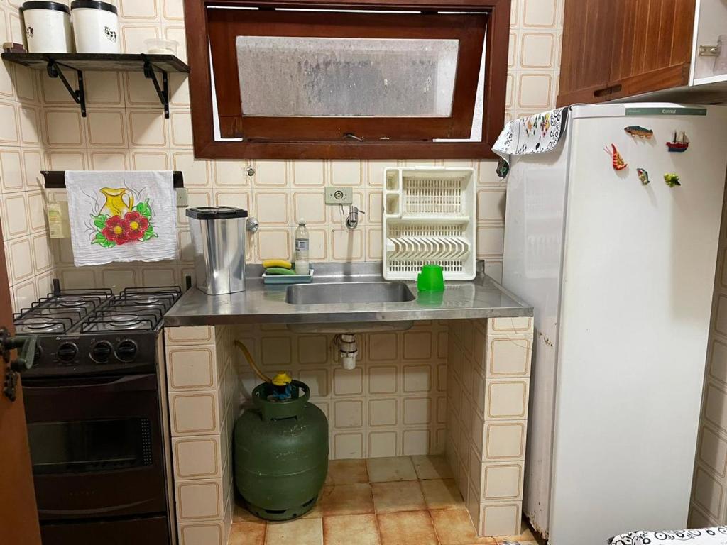 una pequeña cocina con fregadero y nevera. en Apartamento para Temporada Ubatuba, en Ubatuba