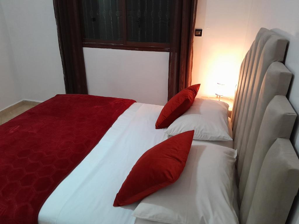 - un lit rouge et blanc avec des oreillers rouges dans l'établissement Welcome Home, à Béni Mellal