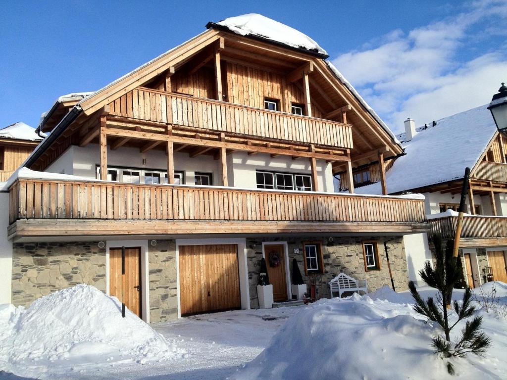 a large wooden house with snow in front of it at Schneeweiss in Mauterndorf