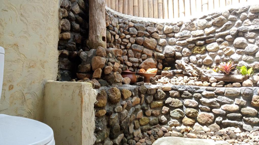 a stone wall in a bathroom with a toilet at duegoal farmhouse in Jatiluwih