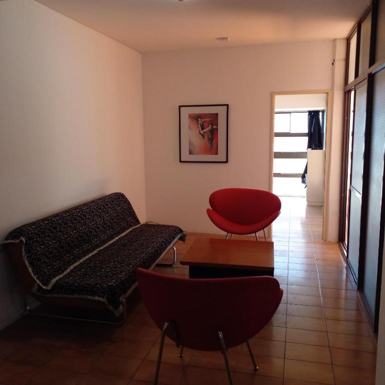 a living room with a couch and a red chair at Amplio departamento zona centro in Paraná