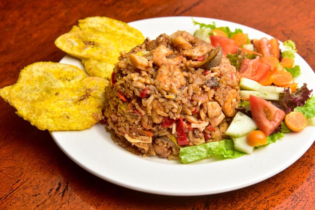 un plato blanco de comida con ensalada y patatas fritas en Playa Mareygua Hostal, en Buritaca