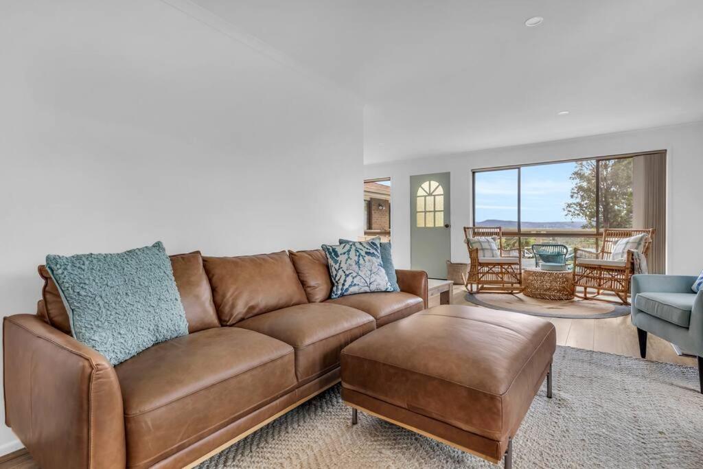 Una sala de estar con un sofá marrón y una mesa. en Seaglass at Pambula Beach, en Pambula Beach