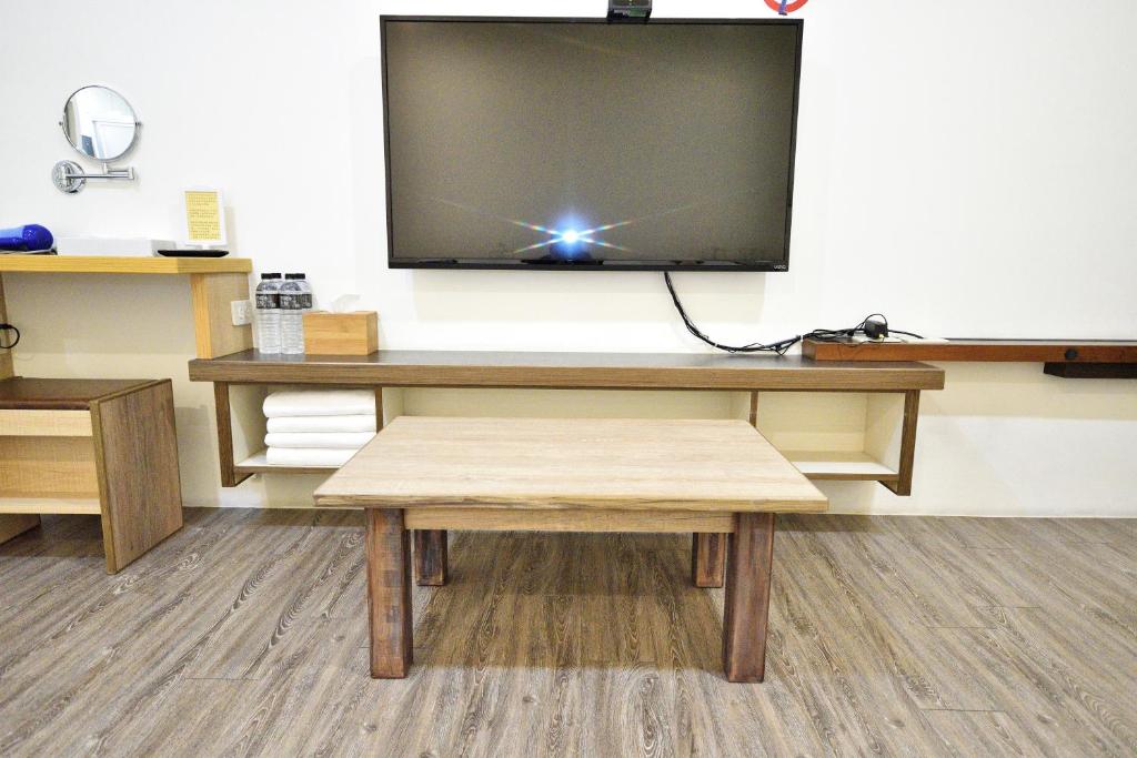 a desk with a television on a wall with a bench at Jamie home stay in Taitung City