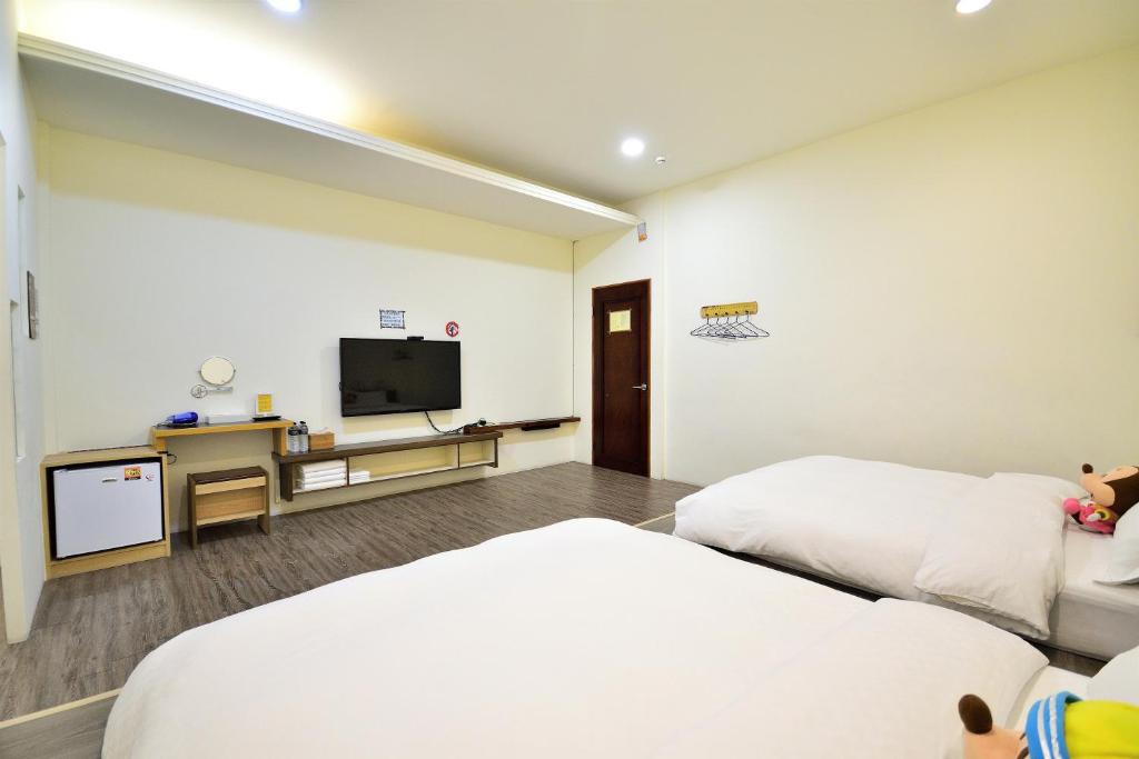 a hotel room with two beds and a flat screen tv at Jamie home stay in Taitung City