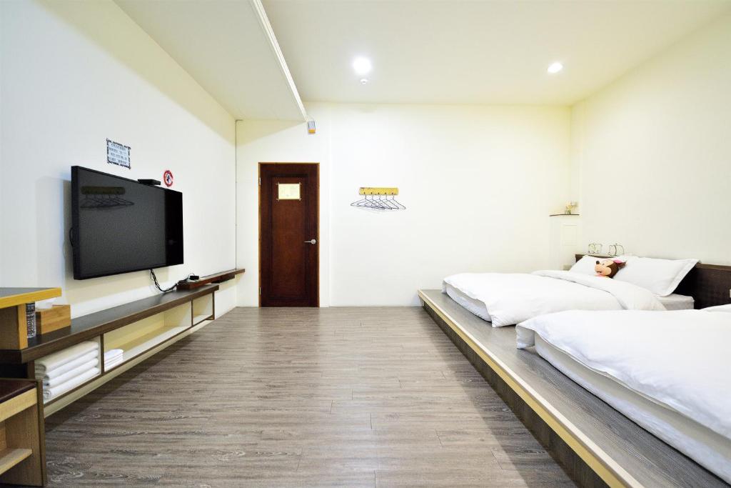 a bedroom with two beds and a flat screen tv at Jamie home stay in Taitung City