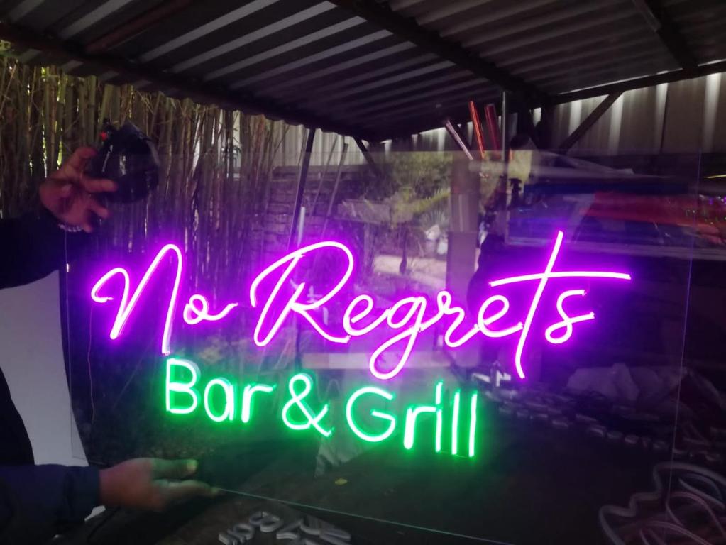 un letrero de neón que dice que no se arrepiente del bar y la parrilla en No Regrets en Coxen Hole