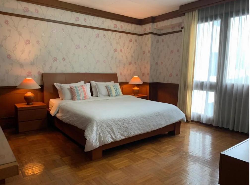 ein Schlafzimmer mit einem Bett, zwei Lampen und einem Fenster in der Unterkunft Park Royale Apartments, Senayan, Jakarta in Jakarta