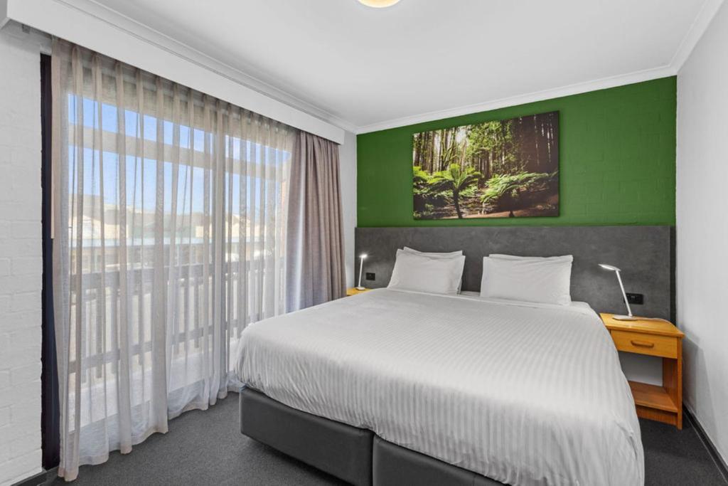 Apollo Bay Motel & Apartments, BW Signature Collection في خليج أبولو: غرفة نوم بسرير كبير وجدار أخضر