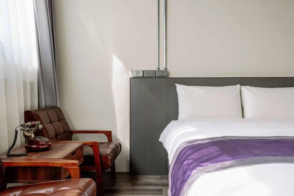 um quarto com uma cama, uma mesa e uma cadeira em Saturn Hotel em Taichung