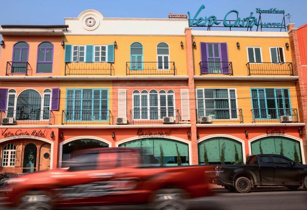 un camion rouge conduisant devant un bâtiment dans l'établissement Vera Costa Hotel, à Nong Khai