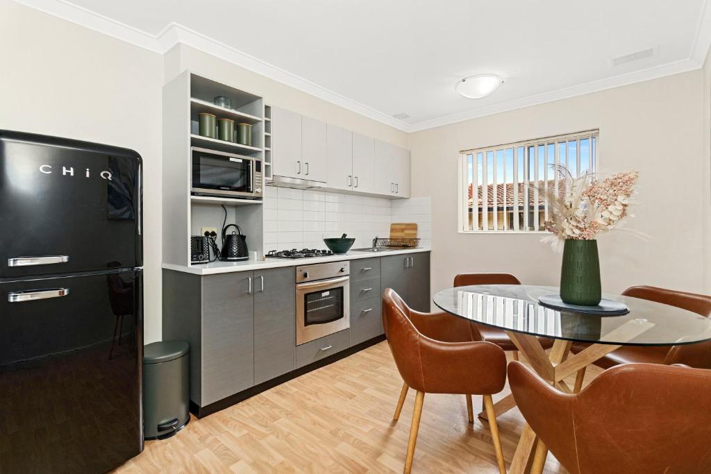 uma cozinha com uma mesa e um frigorífico preto em 8 Cute Cunningham Close To Subiaco - Sleeps 4 em Perth