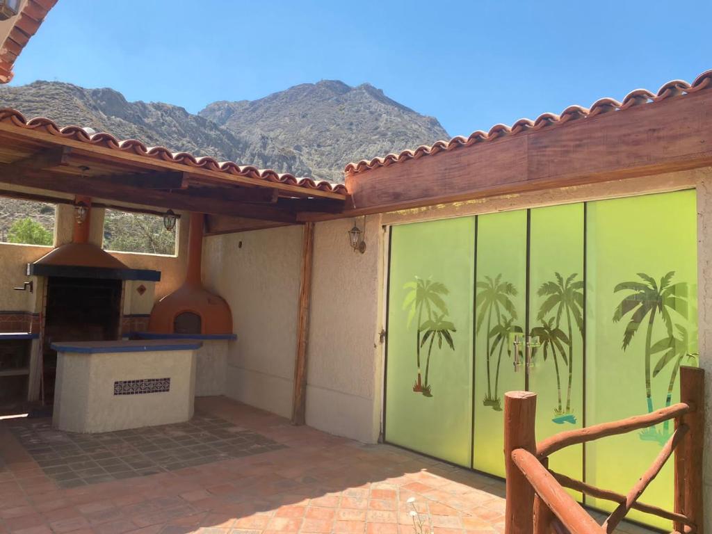 a green garage door with palm trees painted on it at Casa de Campo Buganvilllas in Mecapaca