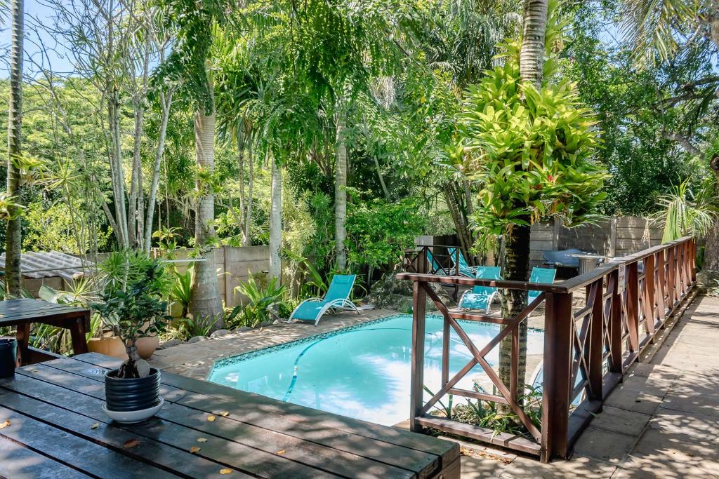 een zwembad met een houten terras en een tafel en stoelen bij African Dreamz Guest House in St Lucia