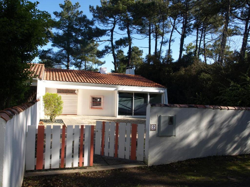 une clôture blanche devant une maison blanche dans l'établissement Charmante maison rénovée en lisière de forêt, 600m de la plage, 2 jardins clos, confort moderne - FR-1-323-371, à Saint-Jean-de-Monts