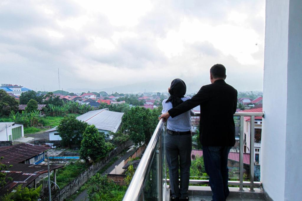 um homem e uma mulher de pé numa varanda a olhar para uma cidade em Sepanak Hotel by Amazing em Curup