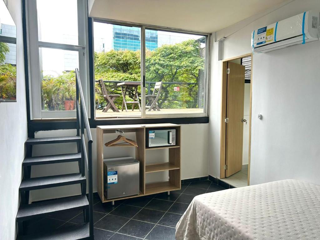 um pequeno quarto com uma cama e uma janela em Habitación independiente con Terraza en el centro de provenza y P.Lleras em Medellín