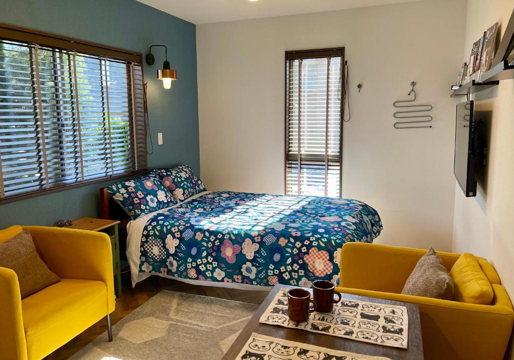 een slaapkamer met een bed en twee stoelen en een televisie bij Kiwi House Tokoname VACATION STAY in Tokoname