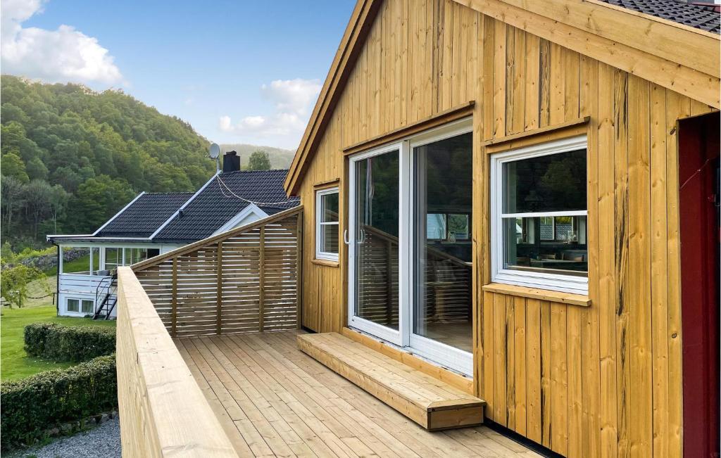 una terrazza in legno accanto a una casa con finestre di 2 Bedroom Stunning Home In Lyngdal a Lyngdal