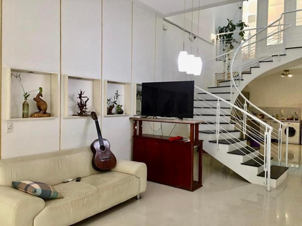 een woonkamer met een bank met een gitaar en een trap bij Gia Khôi Homestay in Hue