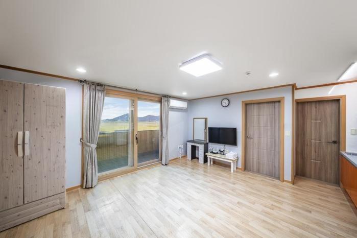 a large living room with wooden floors and a large window at Yongmaru Pension in Suncheon