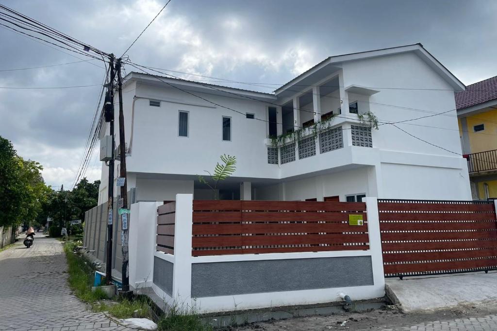 a white house with a wooden fence in front of it at OYO 93457 White House Syariah in Kubang