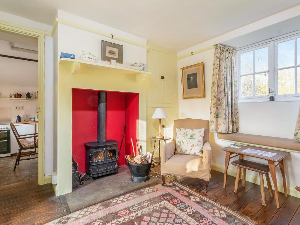 Gore Cottage في Powerstock: غرفة معيشة مع موقد خشبي وكرسي