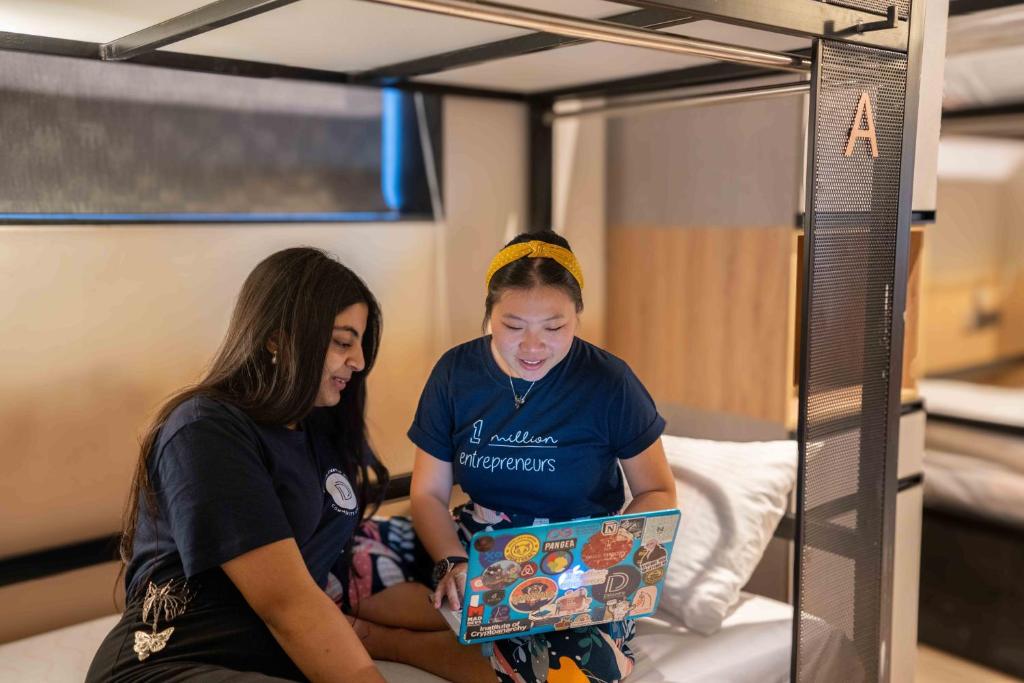 two girls sitting on a bunk bed with a laptop at Draper Startup House for Entrepreneurs Hyderabad in Hyderabad