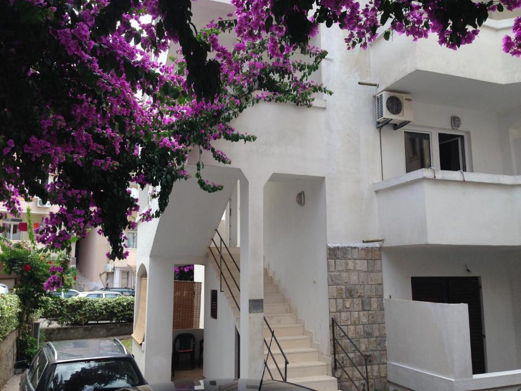 a white building with stairs and purple flowers at Guest House Violet in Bečići