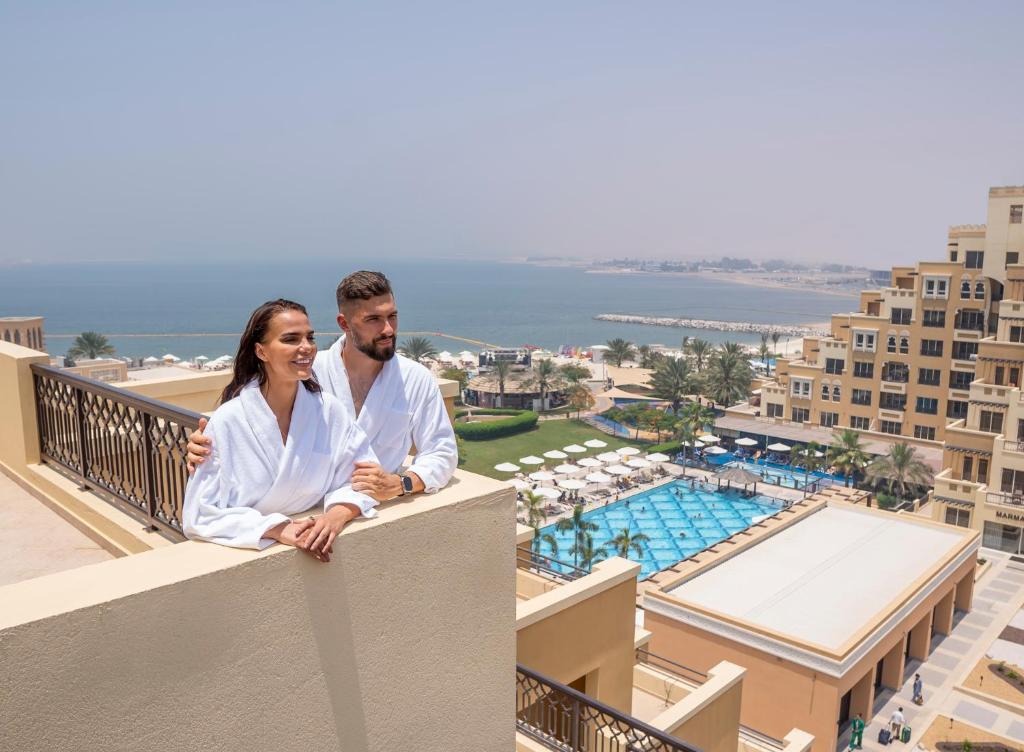 a man and a woman sitting on a balcony of a resort at Rixos Bab Al Bahr - Ultra All Inclusive in Ras al Khaimah