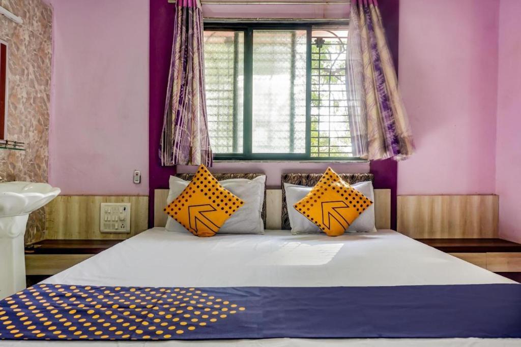 a bedroom with a bed with yellow pillows and a window at Hotel Anupark in Sakri
