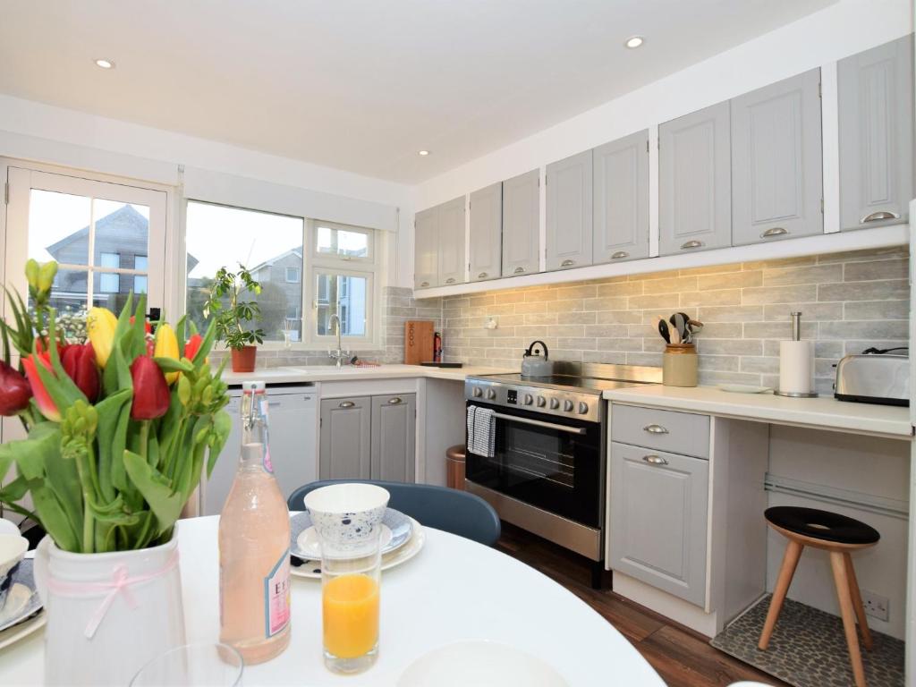 a kitchen with white cabinets and a table with flowers at 2 Bed in Widemouth Bay 55833 in Marhamchurch