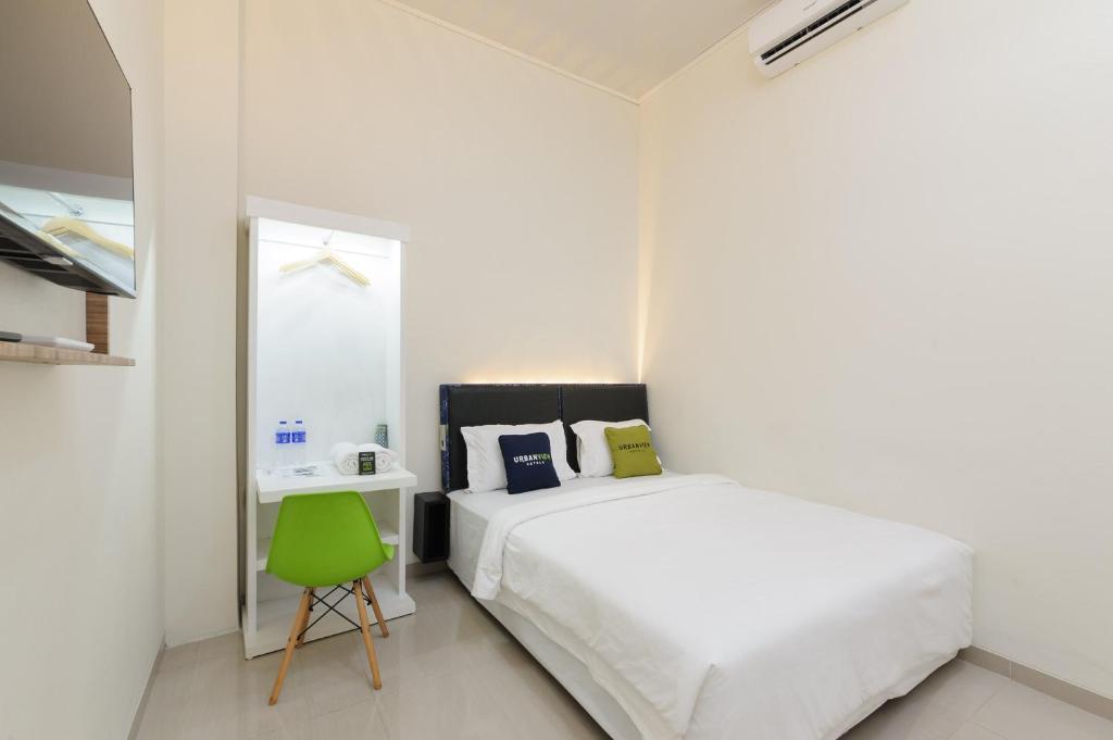 ein weißes Schlafzimmer mit einem Bett und einem grünen Stuhl in der Unterkunft Urbanview Hotel Binwa Syariah Bandar Lampung in Hajimana