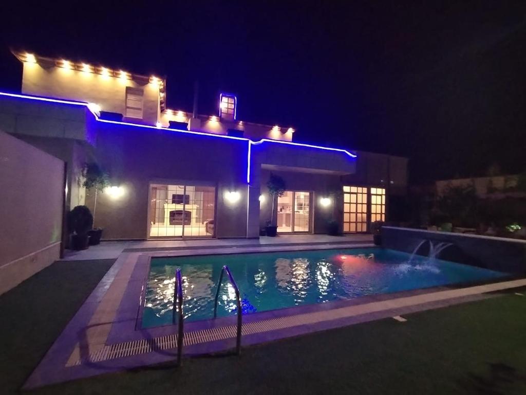 a swimming pool in front of a house at night at The Oaks in Madaba