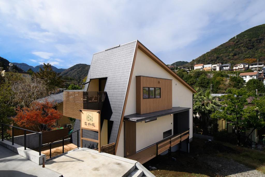 una pequeña casa en una colina con montañas en el fondo en HAKO REIRO 箱・玲瓏 en Hakone