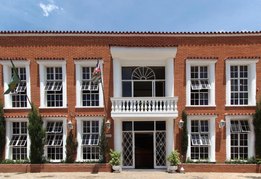 a red brick building with a white balcony at Hotel Santa Rita in Indaiatuba