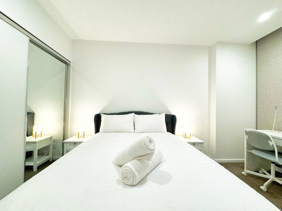 een slaapkamer met een wit bed en handdoeken bij Urban Sanctuary in West Franklin with Pool & Gym in Adelaide